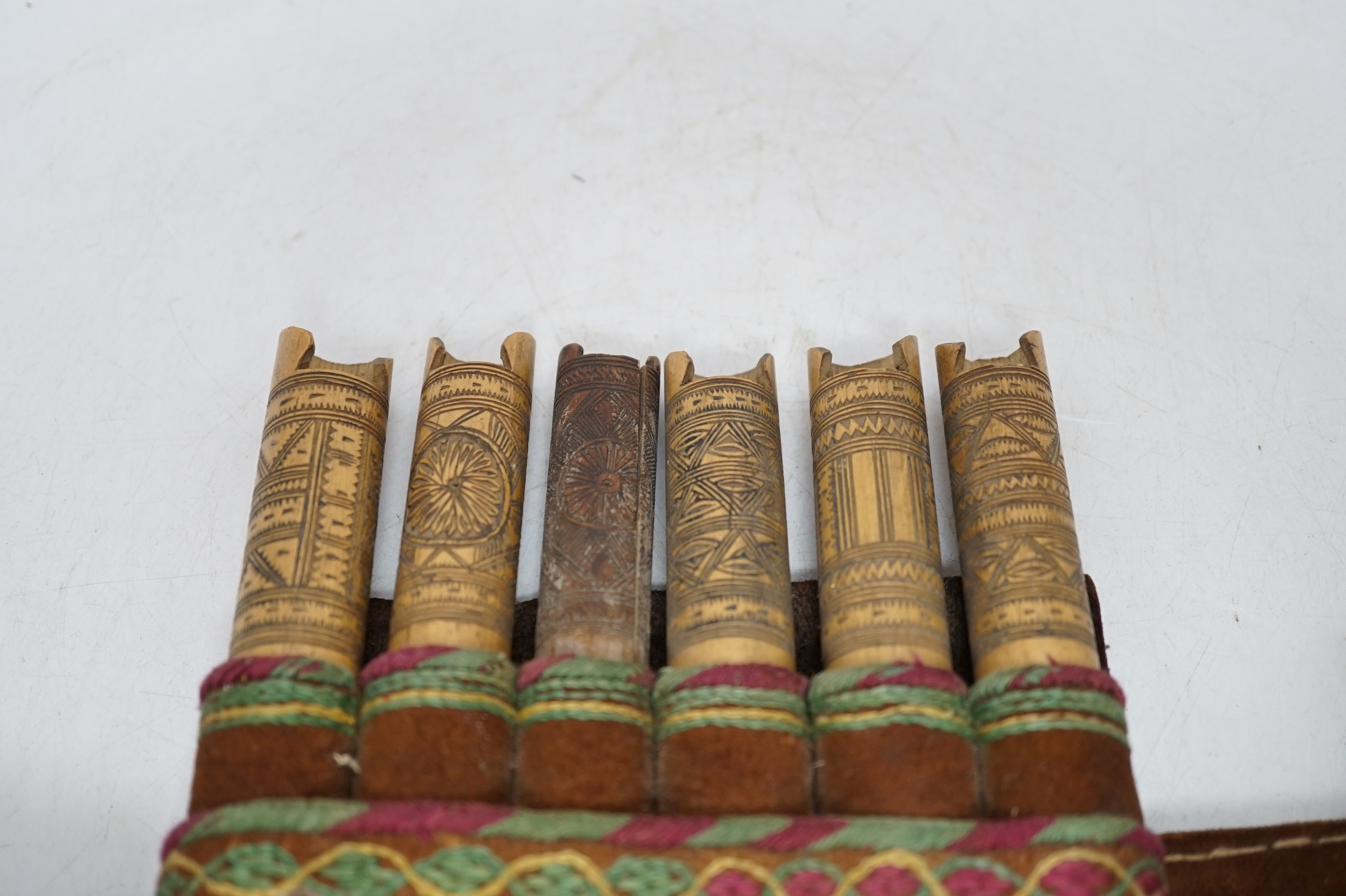 A 19th century Armenian gazyr belt, with decorative silk embroidery on suede and carved bamboo shot and gunpowder containers, 68cm long. Condition - slightly worn from use